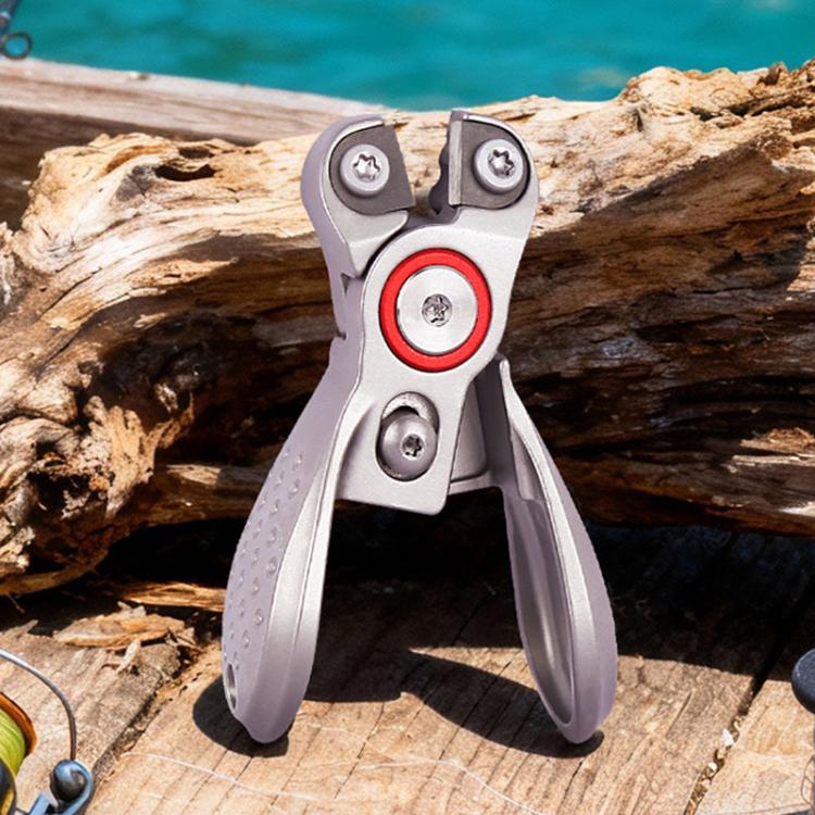Fishing line cutter pliers on a wooden log, silver body with red ring detail