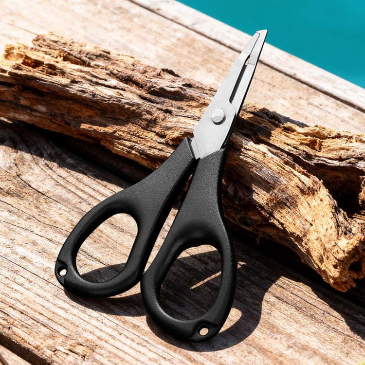 Fishing line cutter pliers with black grips and stainless steel cutting jaws on wood