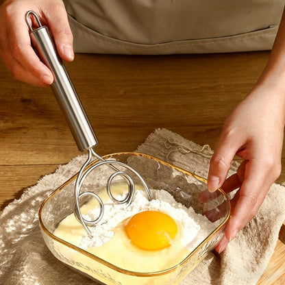 Stainless steel double-coil cream whisk with cylindrical handle, held above a bowl