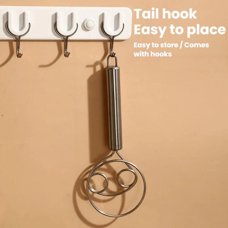 Stainless steel double-coil whisk hanging on wall hooks by the handle