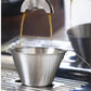 Stainless steel coffee cup with pointed spout pouring into another cup on drip tray