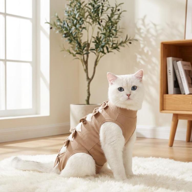 Breathable cat recovery suit in tan/coffee with ribbon bow trim, worn by kneeling cat