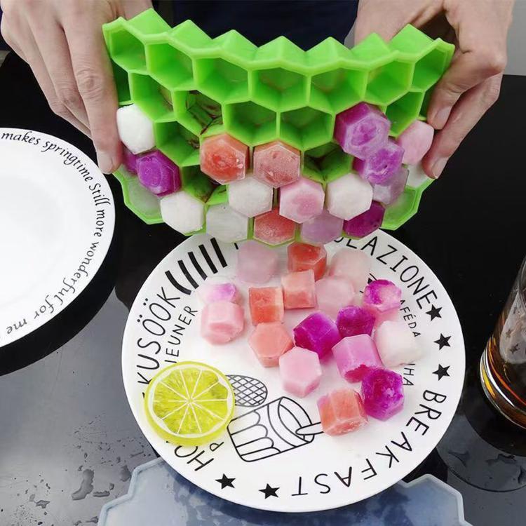 Honeycomb silicone ice cube tray holding colorful cubed ice with green tray walls