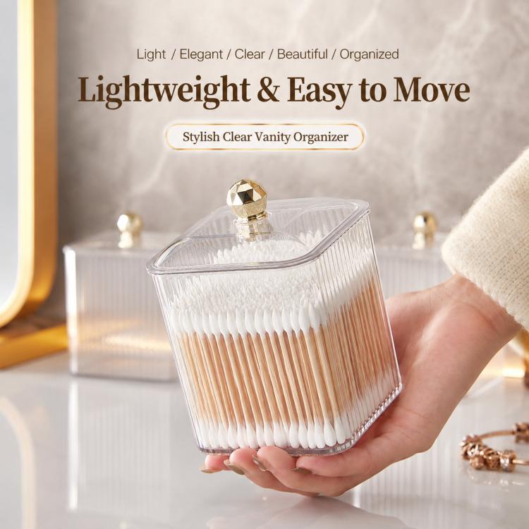 Clear cotton swab holder with gold-knob lid, held in hand