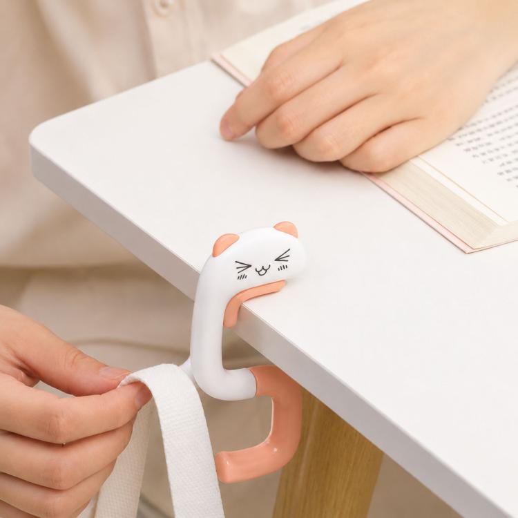 Cat-shaped foldable table bag hook on a desk edge, white with peach handle.