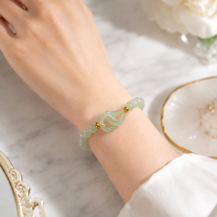 Green jade-style beaded bracelet with interlocking double loop centerpiece on wrist, close-up