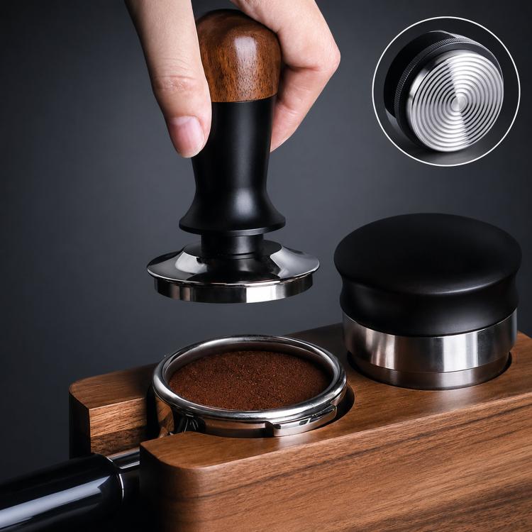 Coffee tamper with walnut wood handle, black body, stainless base, next to a black cap