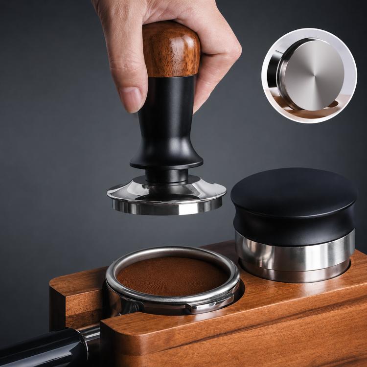 Coffee tamper with walnut wood handle and black body pressing a portafilter on a wooden platform