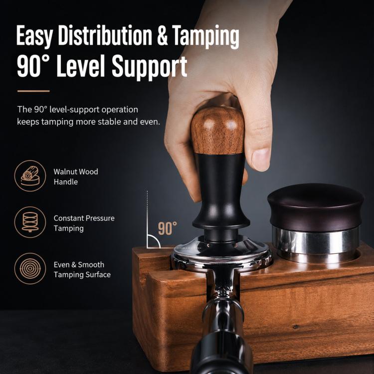 Coffee tamper with walnut wood handle and black body on a wooden base beside portafilter