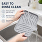 Gray silicone sink tray under faucet flow, sloped ridged surface for rinsing