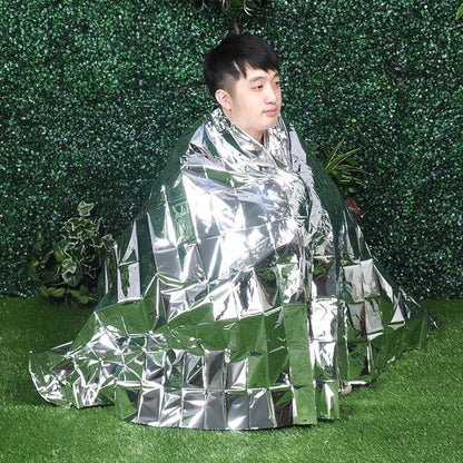 Silver emergency thermal blanket wrapped around a person for outdoor survival