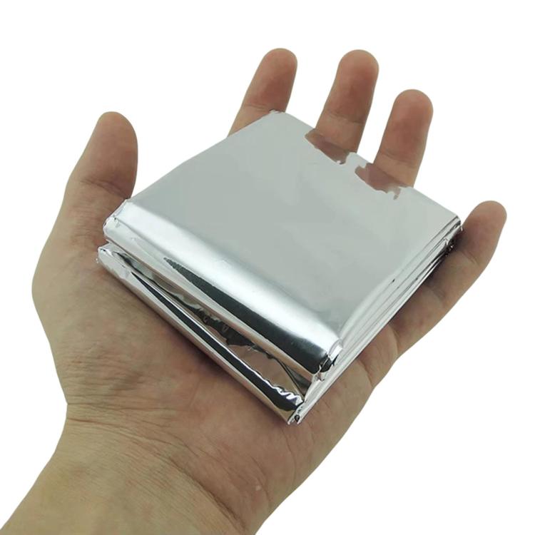 Silver emergency thermal blanket folded in hand, compact travel size