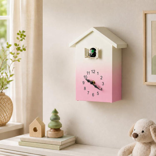 House-shaped wall clock with pink gradient face, black hands, and bird chime window