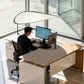 Indoor sunshade curtain in light color over office desk, curved canopy attached to pole