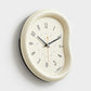 Cream wall clock with light face, minimalist hands and number markers, curved frame