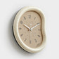 Beige wall clock with taupe face, minimalist hands and number markers, curved frame