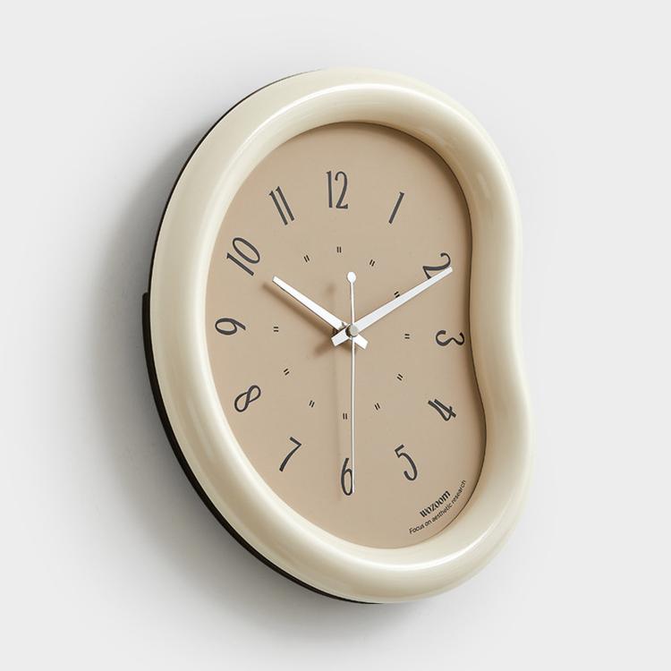 Beige wall clock with taupe face, minimalist hands and number markers, curved frame