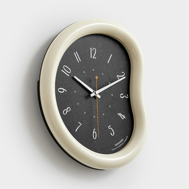 Cream framed wall clock with dark face, minimalist hands and number markers, oval case