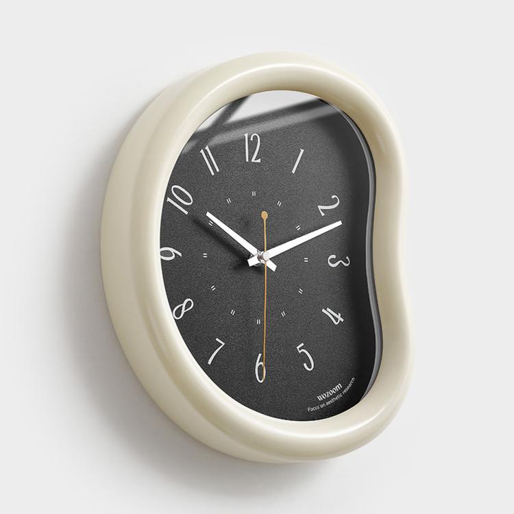 Beige oval wall clock with dark face, minimalist hands and number markers