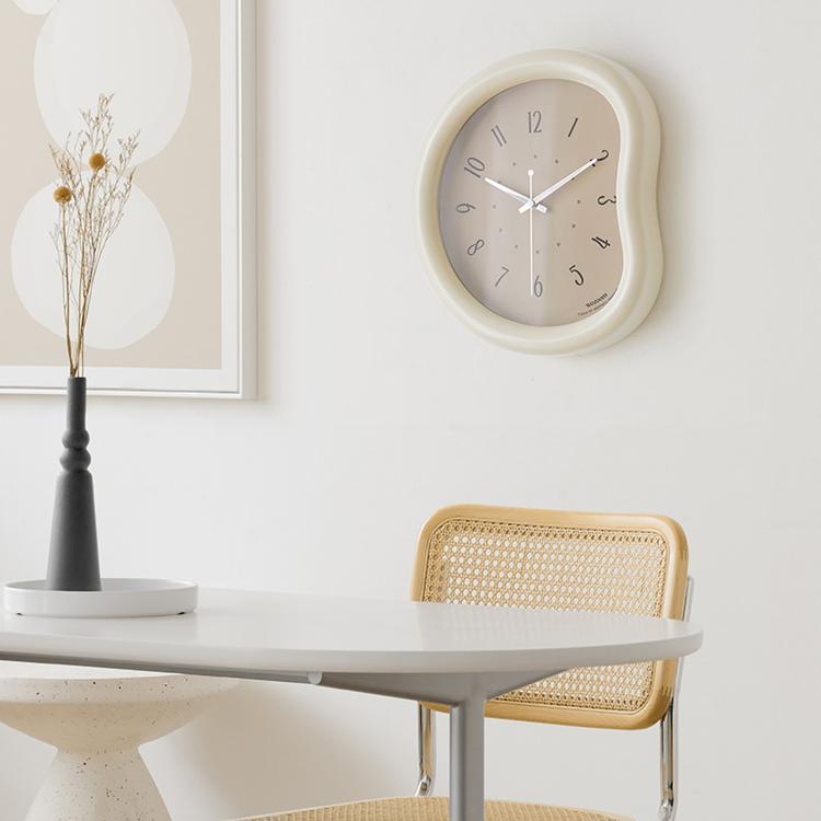 Beige-framed wall clock with light face, minimalist hands and number markers