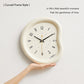 Beige curved-frame wall clock being held up, light face with number markers