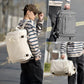 Travel backpack worn by a person, with side straps and a front zip pocket