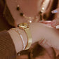 Gold-tone small round watch with ribbed expansion band on wrist, side profile view