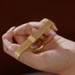 Gold-tone ribbed expansion watch band with small round case, shown in hand