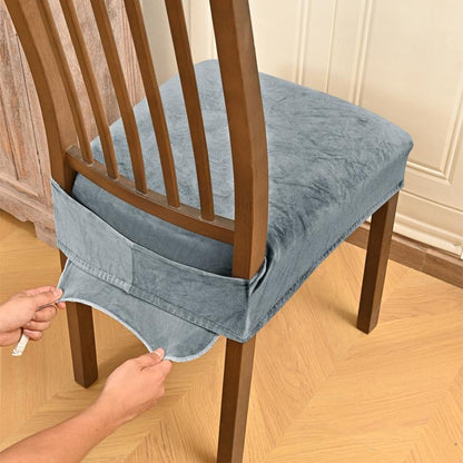 Gray velvet stretch chair seat cover with buckle straps, being fitted on chair