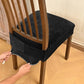Black velvet stretch chair seat cover with buckle straps, being fitted on dining chair