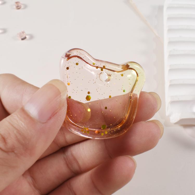 Handheld resin pendant with speckled glitter and a hole at the top for a chain