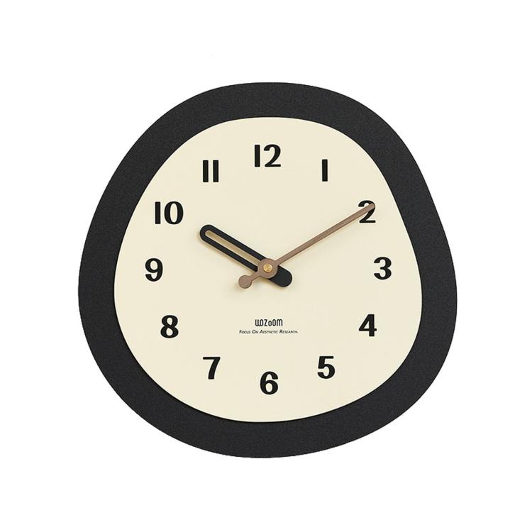 Minimalist oval wall clock close-up with cream dial, dark rim, and gold hands