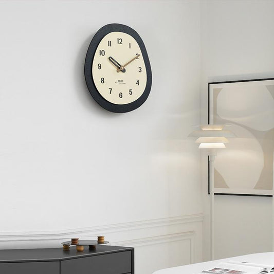Modern oval wall clock with dark outer ring and cream dial showing numbered hours