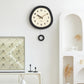 Oval wall clock in dark frame with cream dial and walnut wood hands