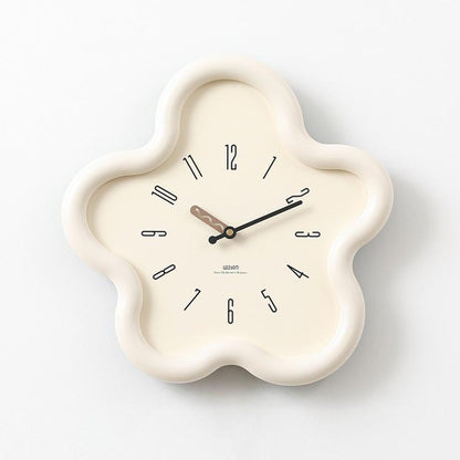 Flower-shaped wall clock with cream frame, beige face, black hands and Arabic numerals.