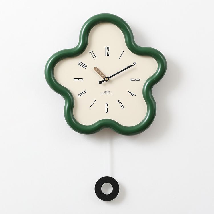Flower-shaped wall clock with green frame, cream face, black hands and Arabic numerals.
