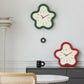 Flower-shaped wall clock with green frame and cream face, black hands and Arabic numerals.