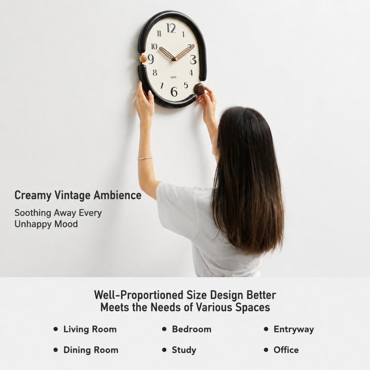 Person hanging a retro oval wall clock with black frame and cream dial.