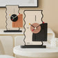 Two geometric desk clocks on a table: cream backs with orange and black side panels
