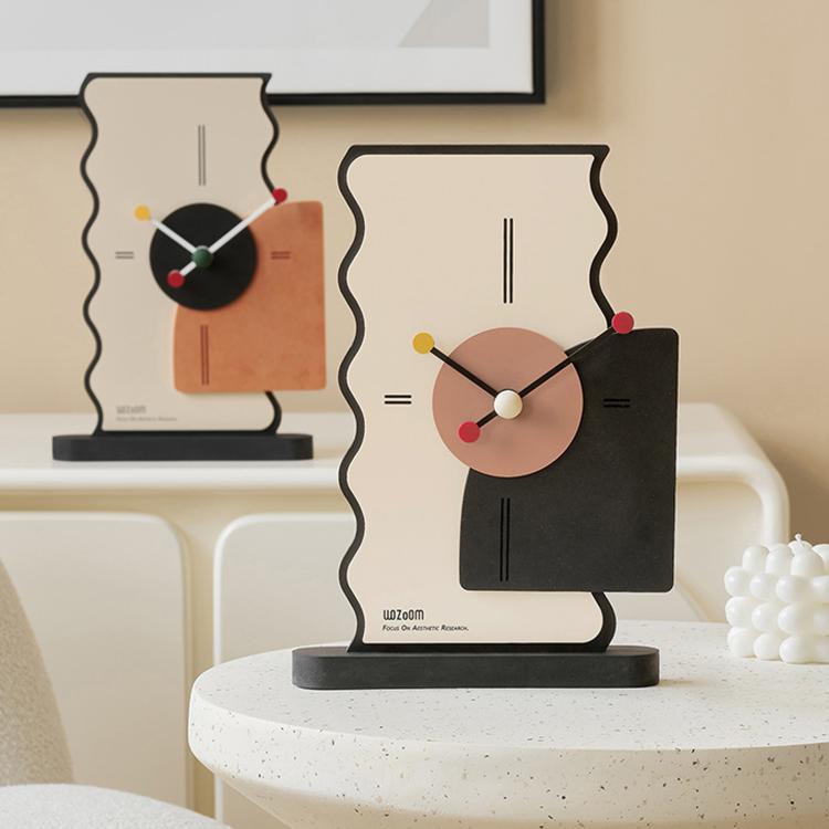 Two geometric desk clocks on a table: cream backs with orange and black side panels