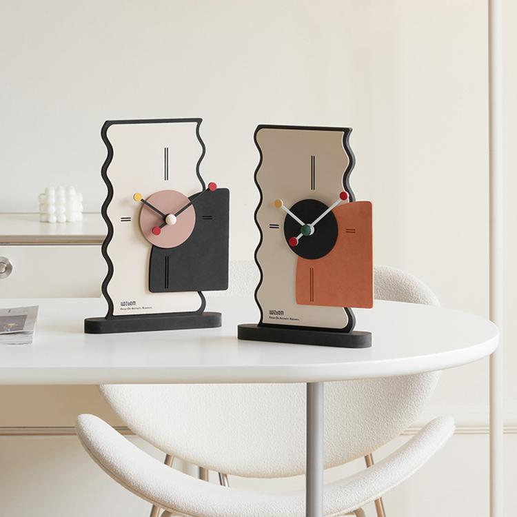 Two geometric desk clocks on a white table: cream backs with black and orange side panels