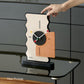 Geometric desk clock with cream back, black dial, and orange panel, held by a hand