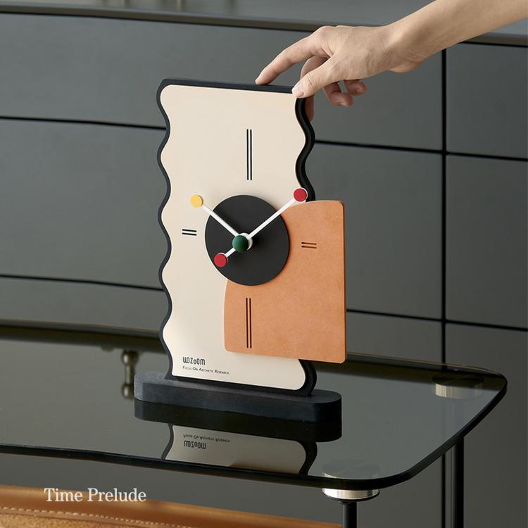Geometric desk clock with cream back, black dial, and orange panel, held by a hand