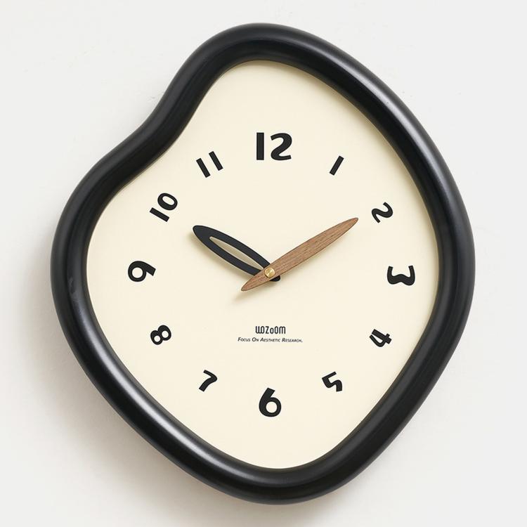 Irregular wall clock with glossy dark frame and cream dial, with gold-toned hands.