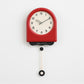 Red pendulum wall clock with cream dial and hanging pendulum weight.