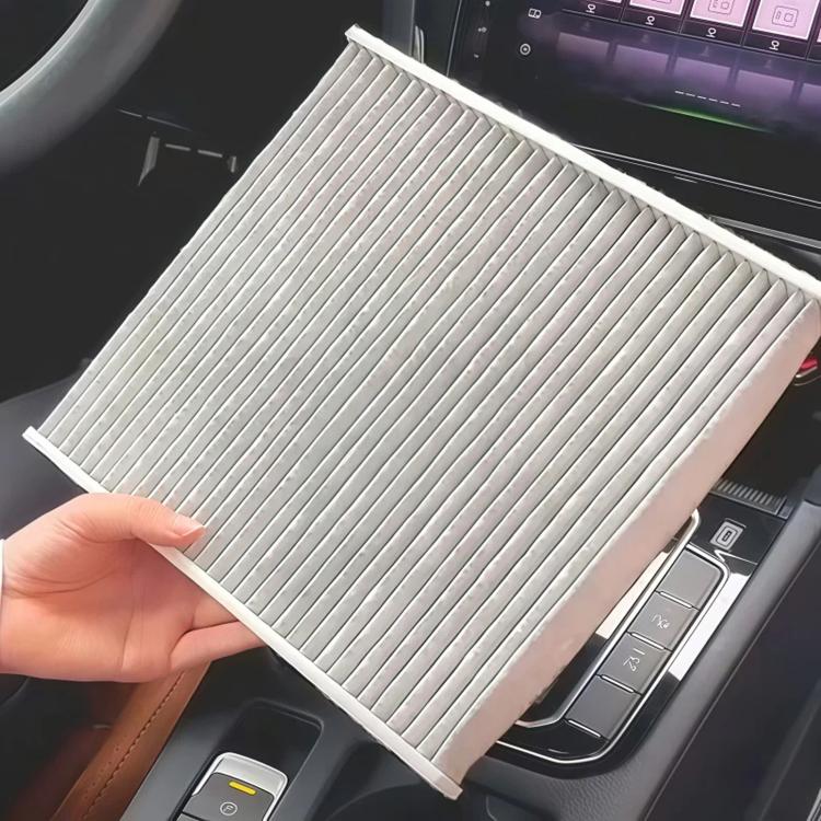 Car air filter element held in hand, gray pleated media with white frame
