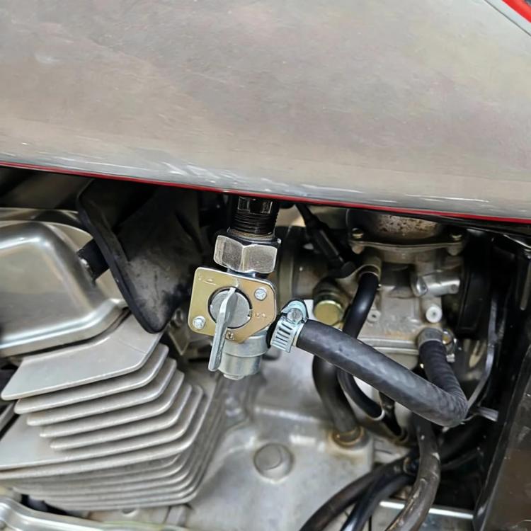 Installed fuel valve switch on motorcycle engine, lever and fuel hose visible