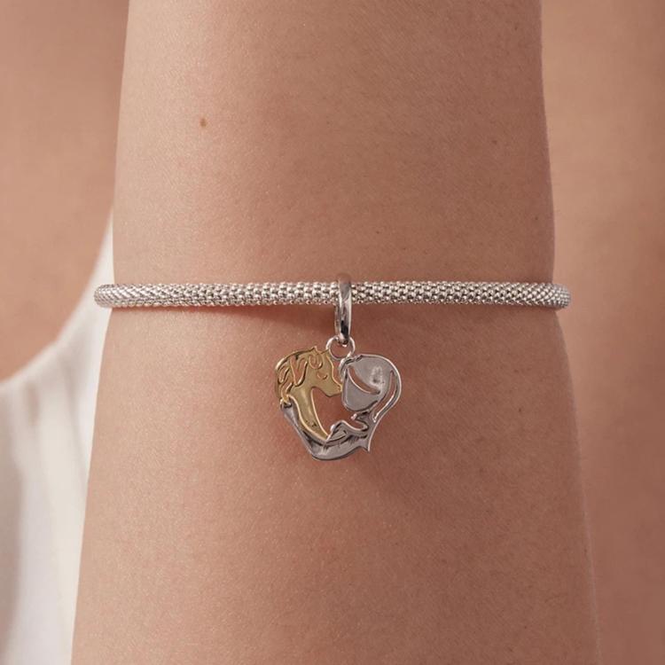 Heart charm bracelet on wrist, silver mesh band with two-tone pendant detail