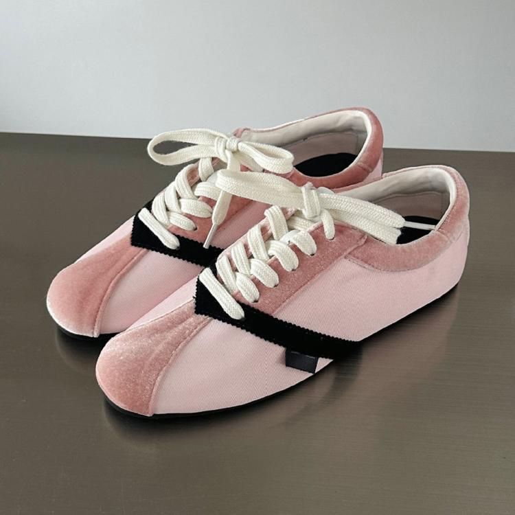 Pair of pink lace-up sneakers with white laces and black side stripe, flat sole