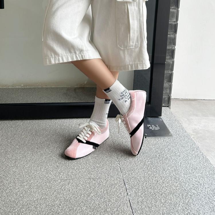 Pink lace-up sneakers worn with white socks, flat low-profile sole